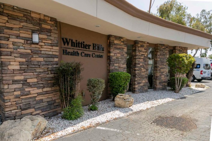 Exterior view of Whittier Hills Health Care Center with stone facade and landscaped surroundings.