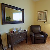 A cozy living room with an armchair, side table, and decorative mirror.