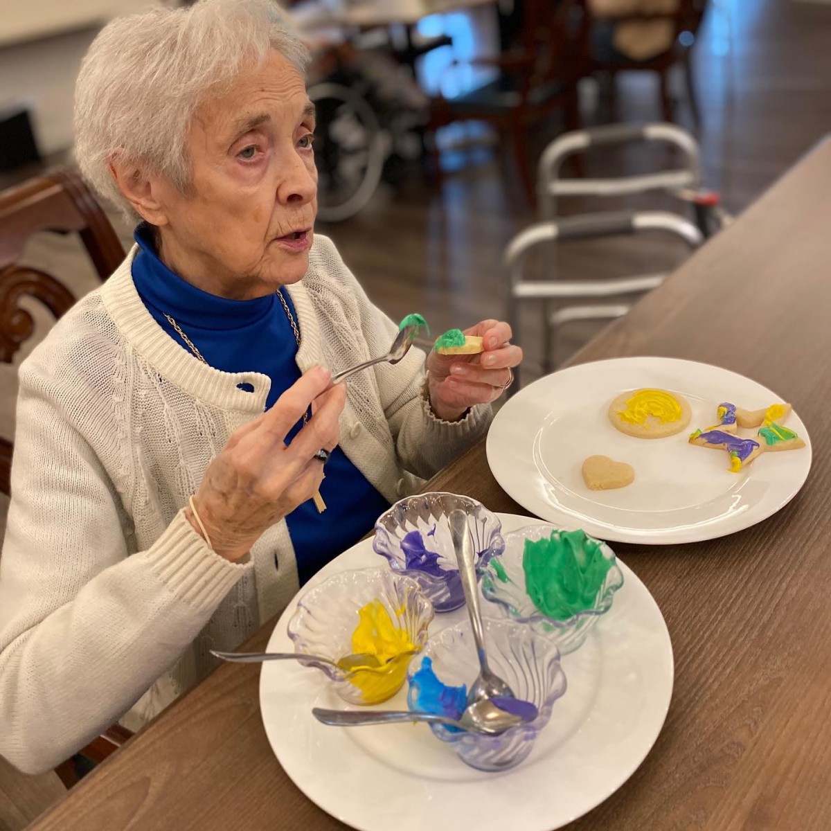 An elderly woman enjoying a colorful dessert at a dining table.