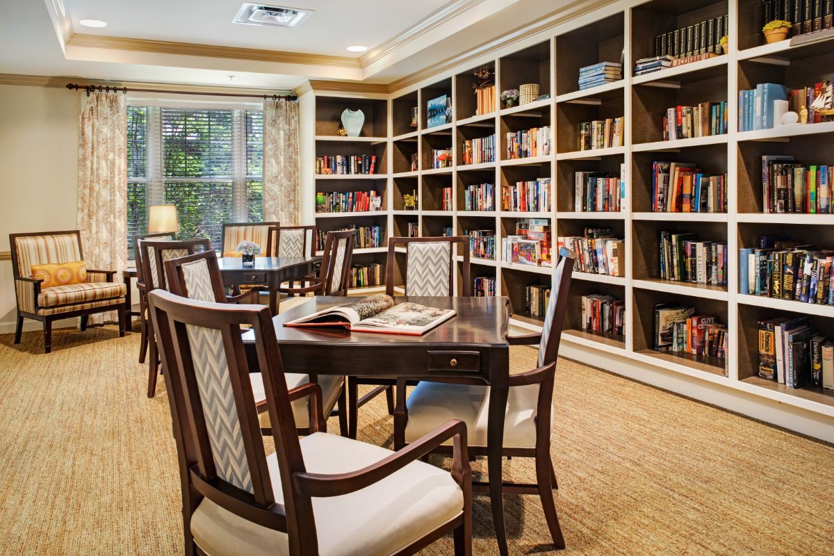 A cozy library with bookshelves filled with books, surrounded by wooden tables and chairs.