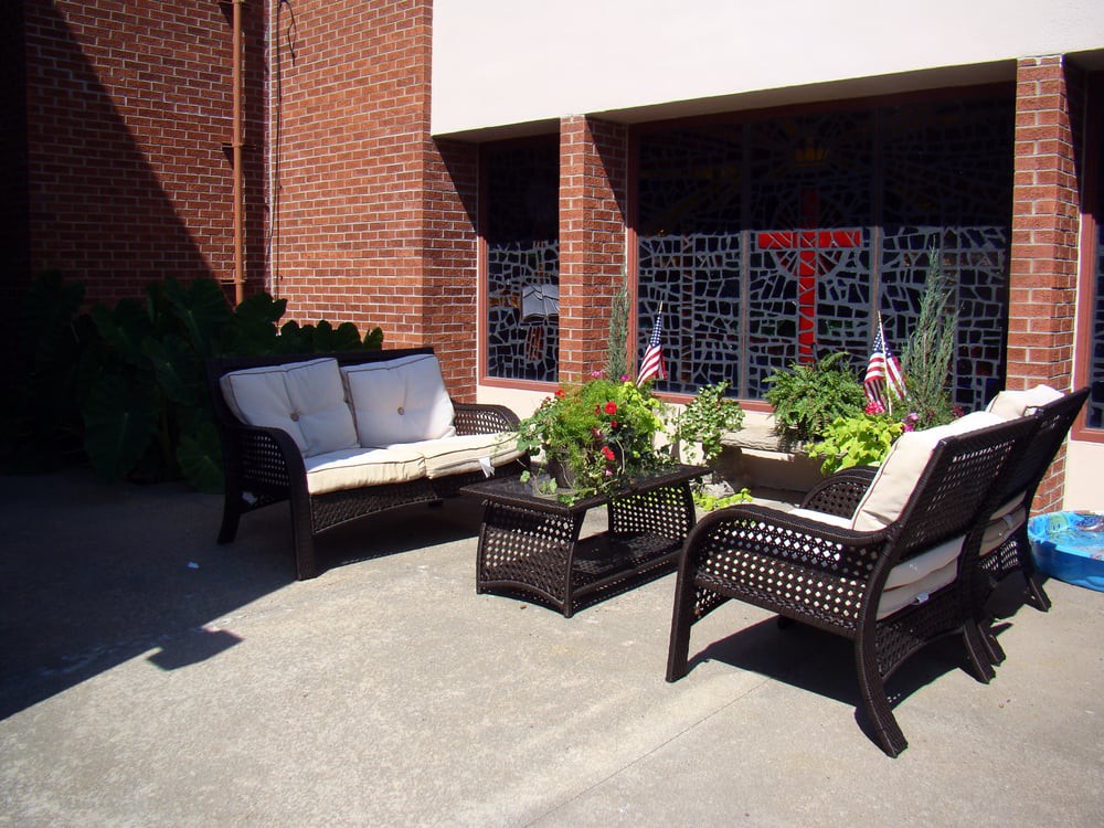 A cozy outdoor patio setup with wicker furniture and plants, basking in the sun.
