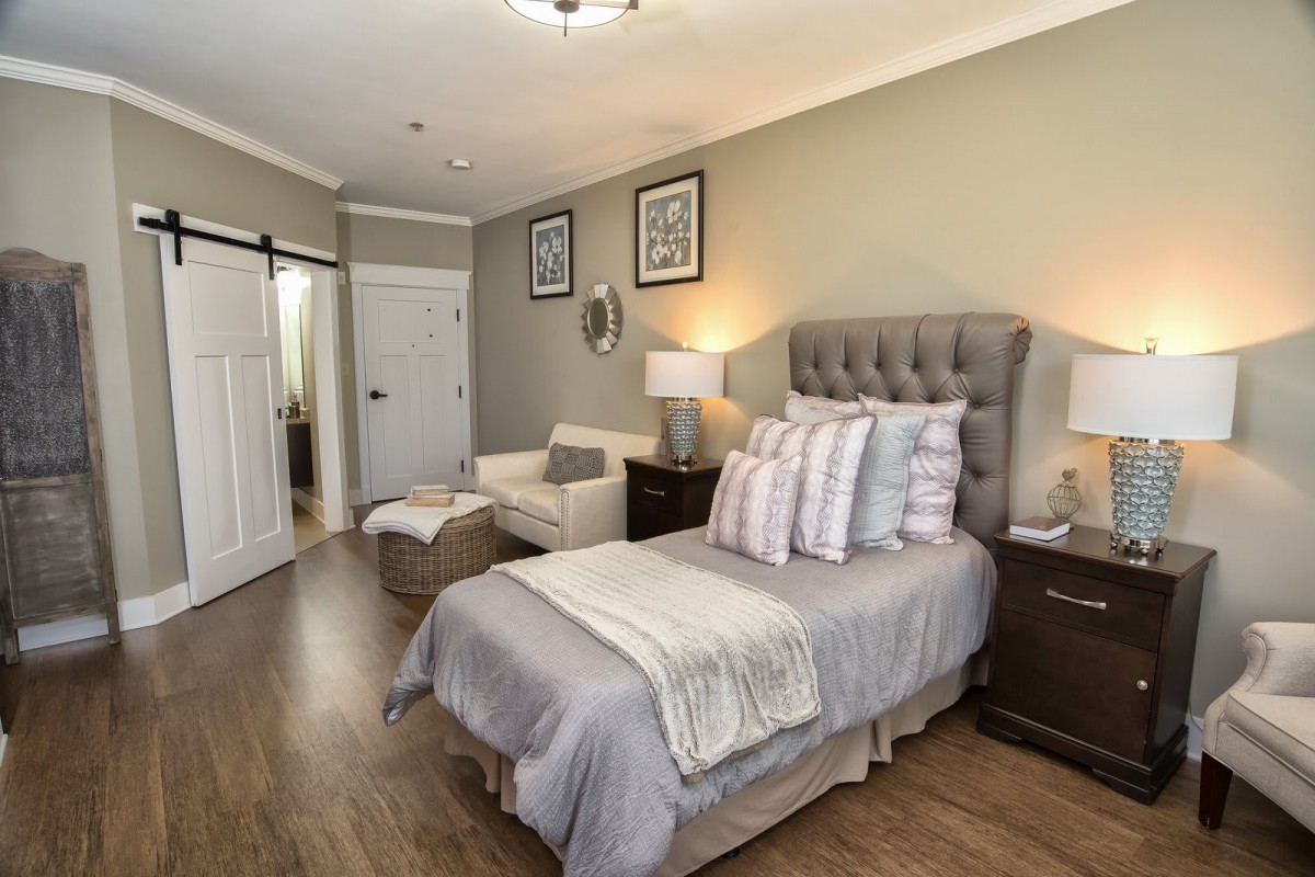 A cozy and modern bedroom with a neatly made bed, an armchair, and elegant decor.