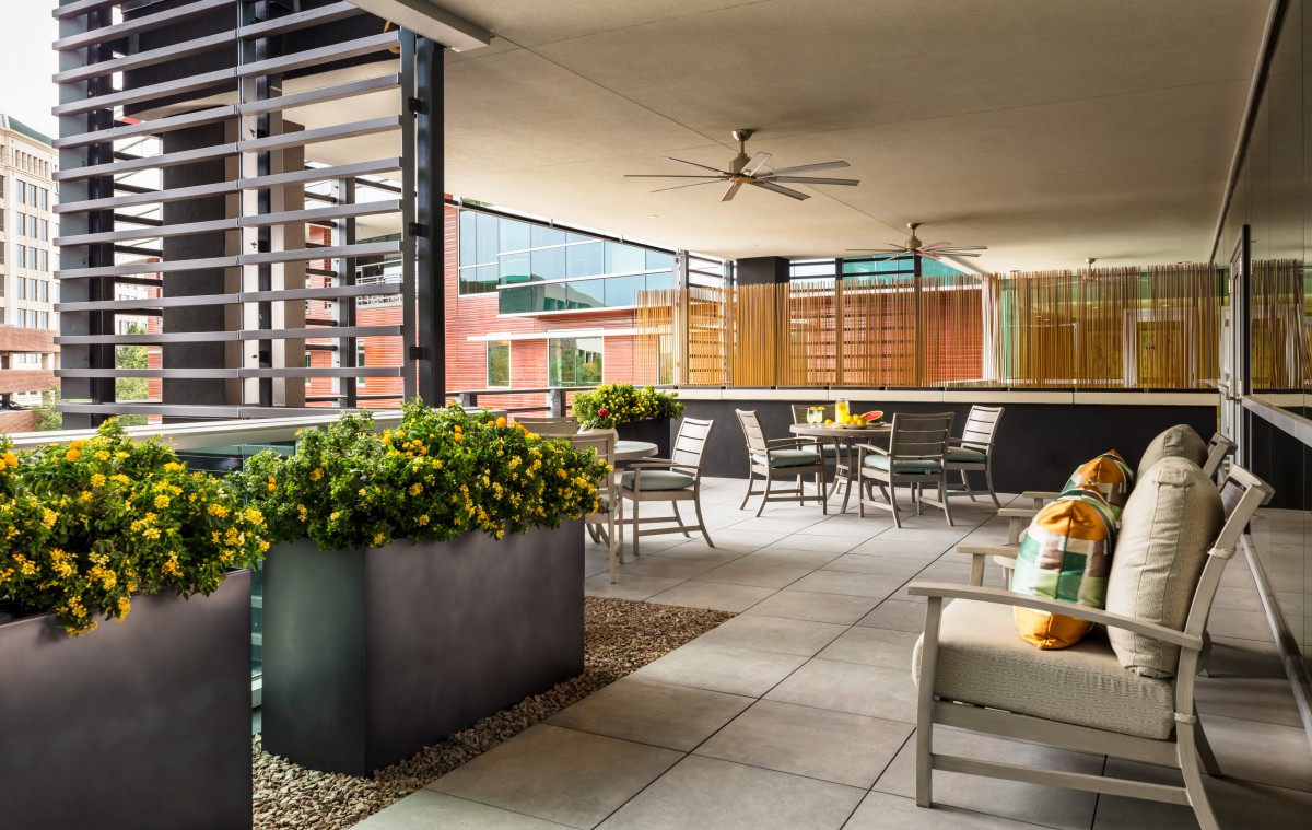 A modern outdoor patio with comfortable seating and lush plants in an urban setting.