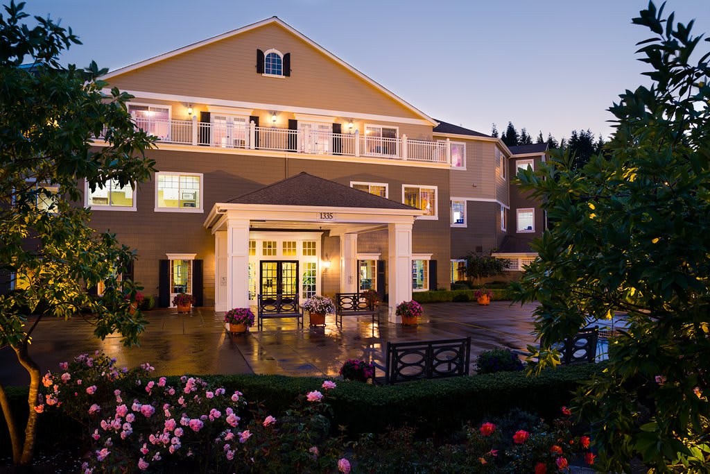 A beautifully lit hotel exterior at dusk with a well-maintained garden.