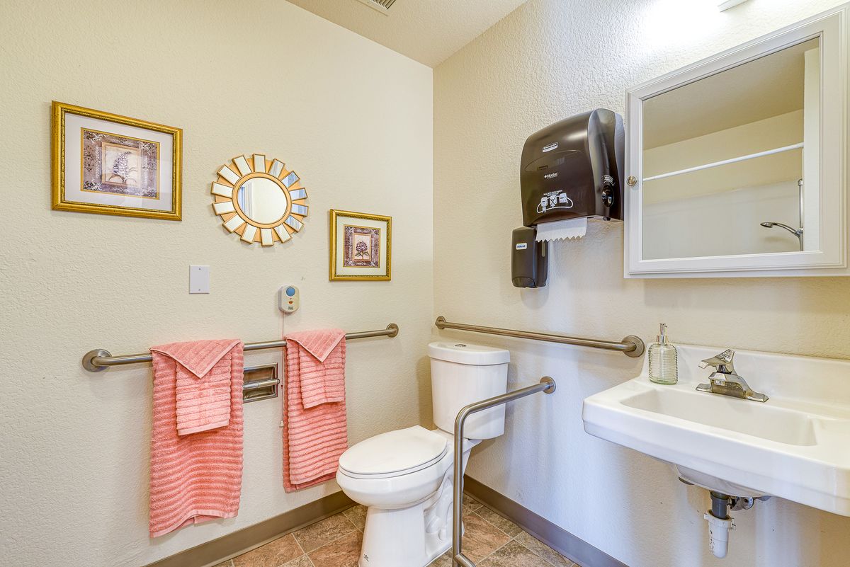 A well-decorated bathroom featuring a toilet, sink, and pink towels with wall art.