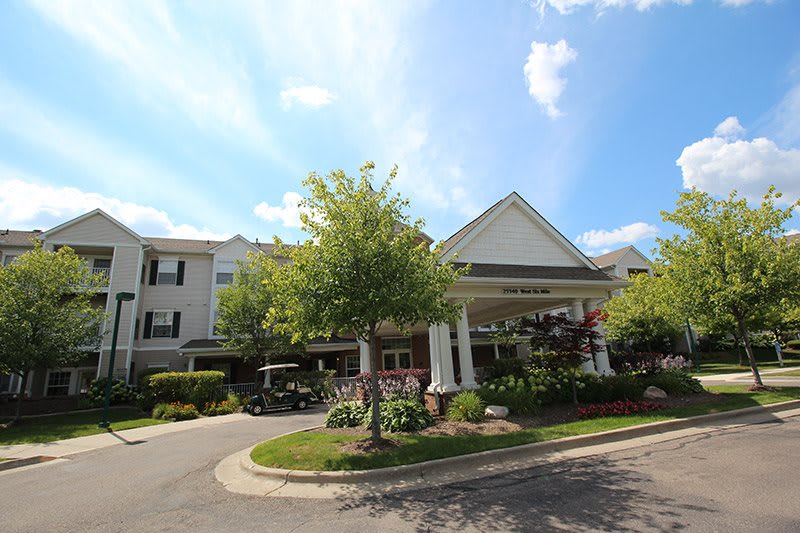 A well-maintained building entrance with lush landscaping and a clear blue sky.