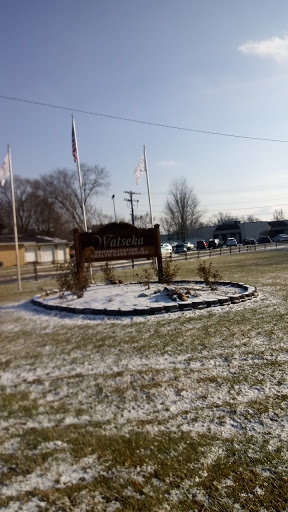 A welcoming sign surrounded by snow and grass, marking a local landmark on a winter day.