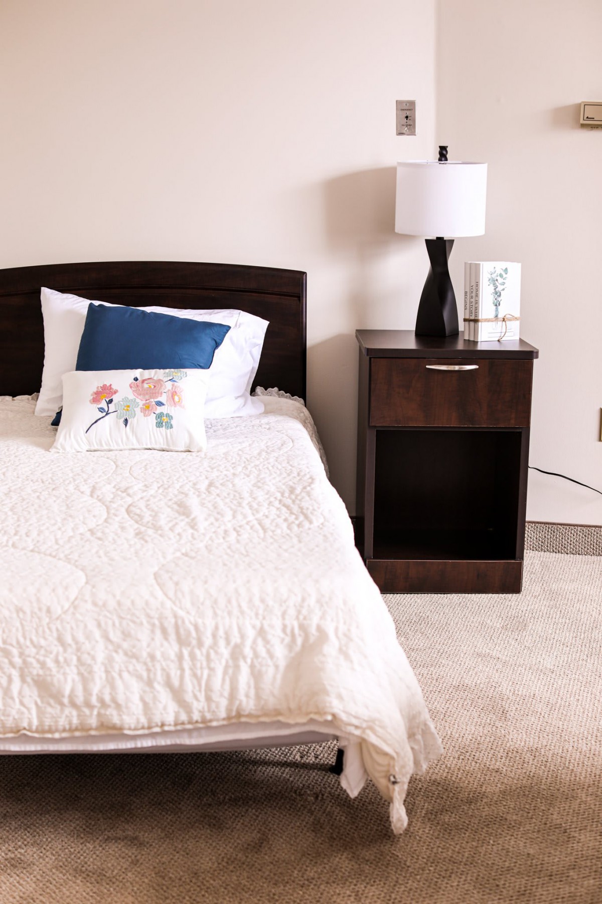 A cozy bedroom with a single bed, nightstand, and lamp.