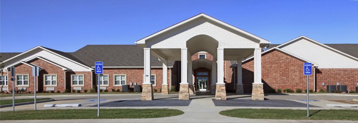 A brick building with a prominent entrance featuring columns and a covered walkway.