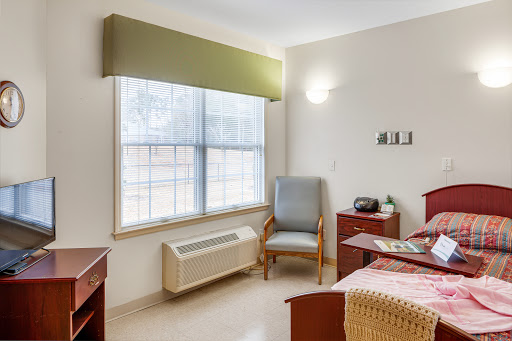 A cozy room featuring a bed, chair, and window, allowing natural light to fill the space.