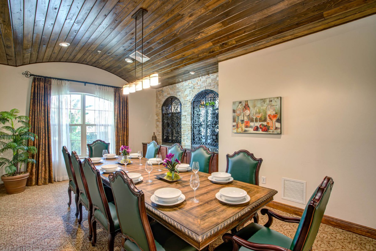 An elegant dining room with a wooden ceiling and traditional furniture, featuring a large table set for a meal.