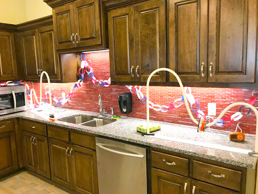 A modern kitchen featuring wooden cabinets, a sleek countertop, and stylish sinks with creative lighting.