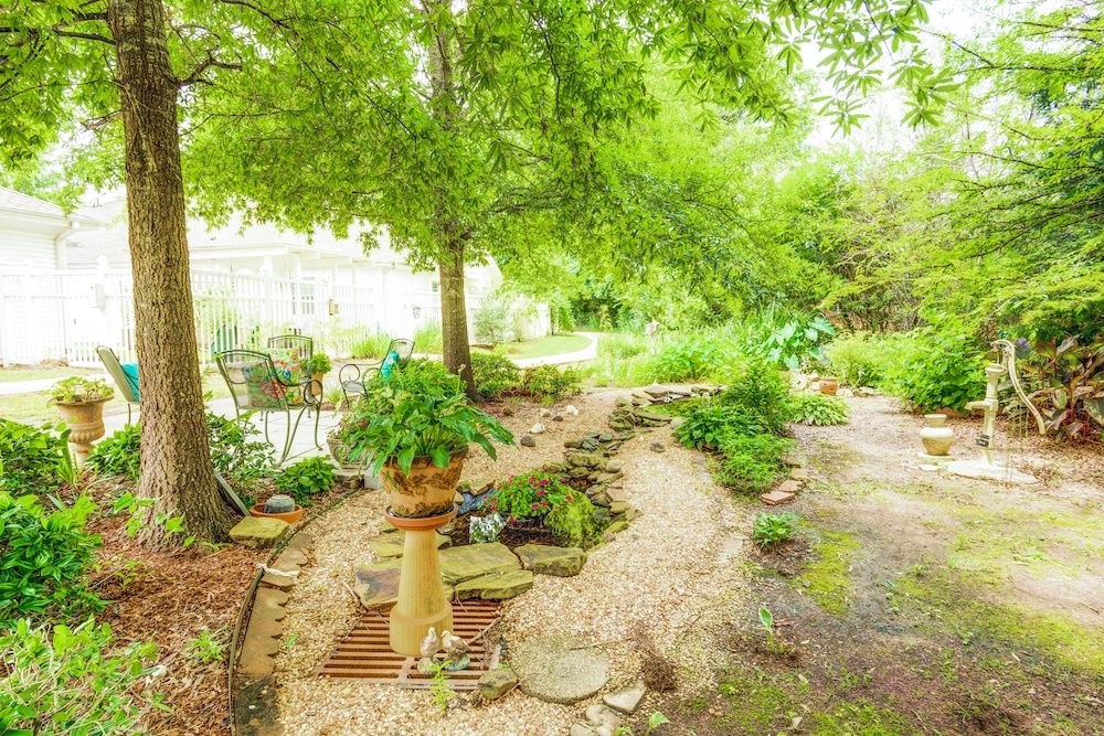 A lush garden with a winding pathway surrounded by trees and various plants.