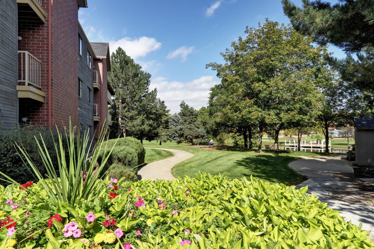A scenic view of a garden walkway surrounded by lush greenery and vibrant flowers.