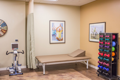 A well-equipped therapy room featuring a treatment table, exercise tools, and decorative artwork.