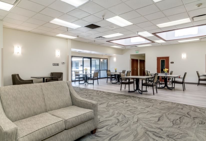 A spacious community lounge featuring comfortable seating, tables, and modern lighting.