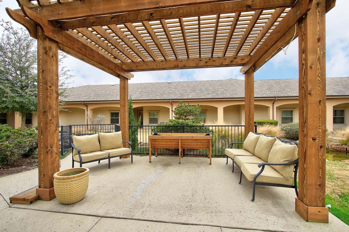 A cozy outdoor patio with a wooden pergola and cushioned seating.