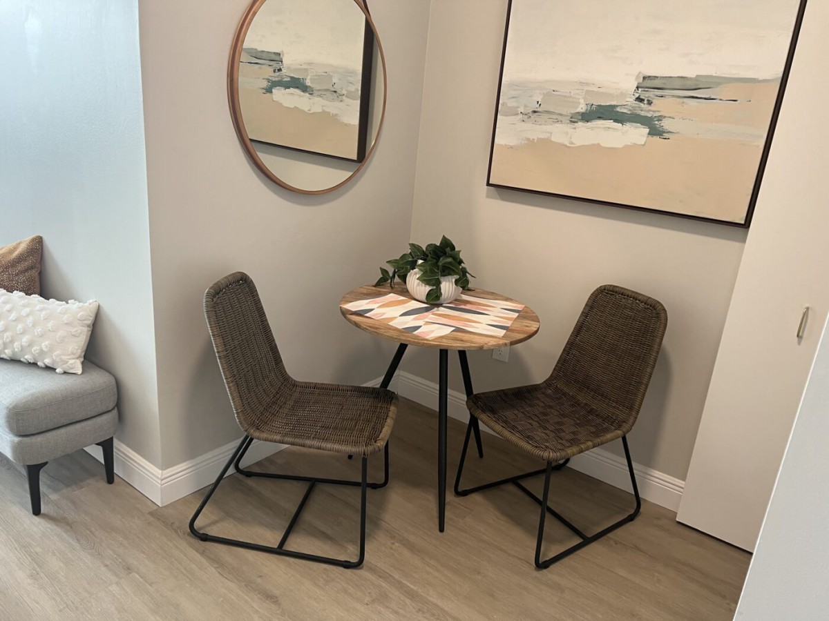 A cozy dining nook with a small round table and two chairs, complemented by wall art and a mirror.