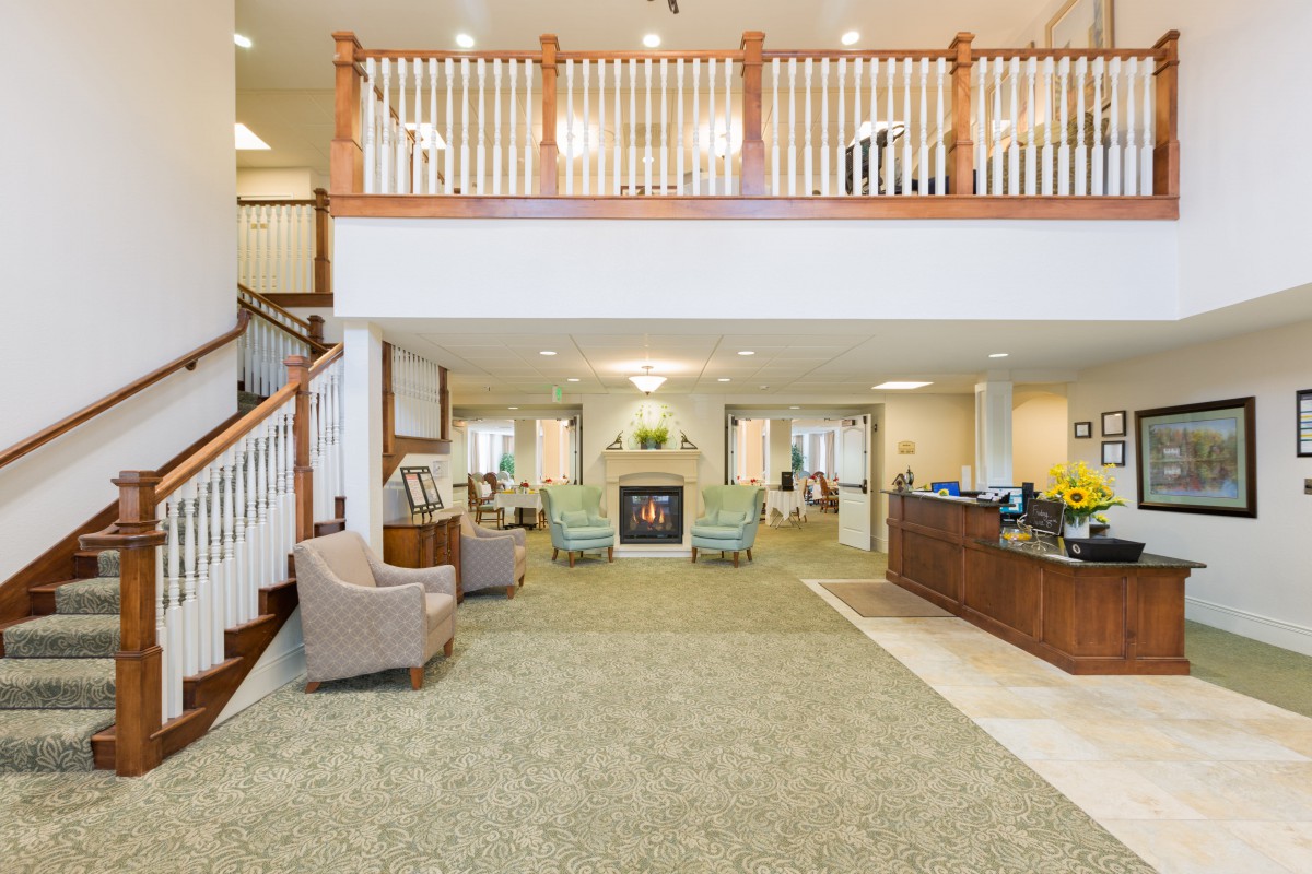 A spacious and well-decorated lobby with a reception desk, staircase, and seating area.