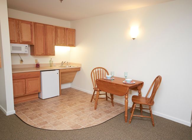 A compact apartment kitchen with a small dining table and chairs.