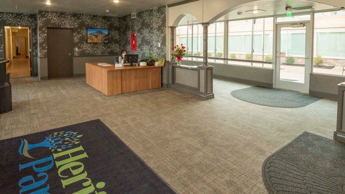A hotel lobby with a reception desk and large windows.