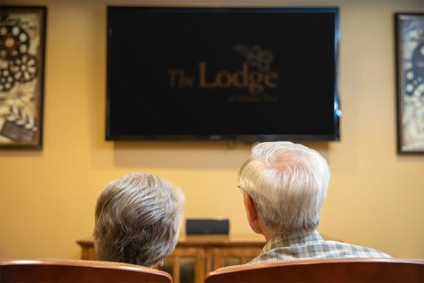 Two seniors watching television in a comfortable setting.