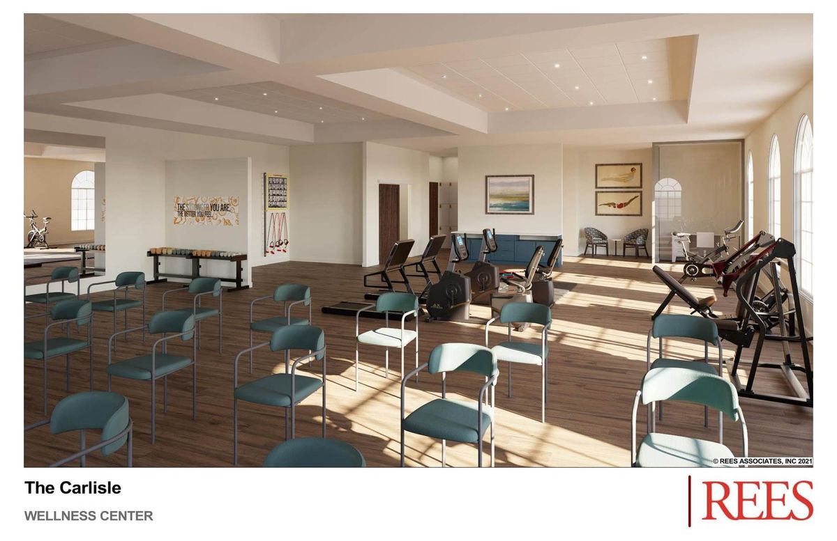 A spacious gym room with exercise equipment and chairs arranged neatly, illuminated by natural light through large windows.