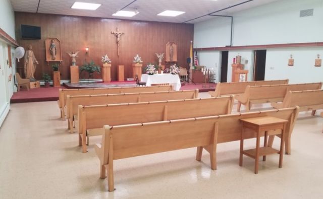 An empty church interior featuring wooden pews and an altar.