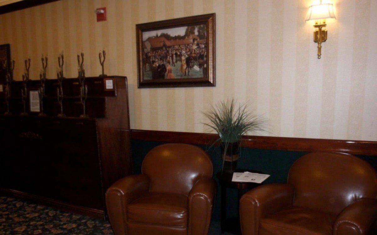 A cozy waiting area with leather chairs, a framed painting on the wall, and a small plant decorating the space.