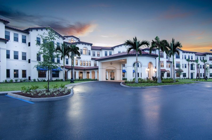 A beautifully lit building surrounded by palm trees at dusk.