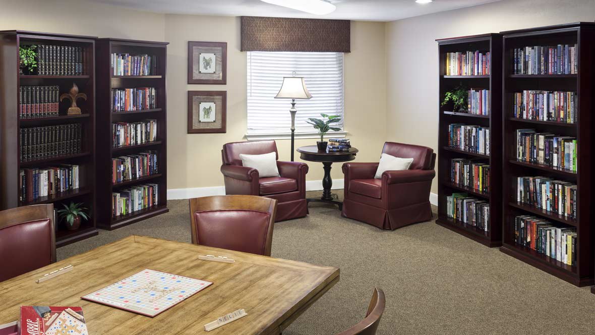 A cozy reading room with bookshelves, comfortable chairs, and a wooden table.