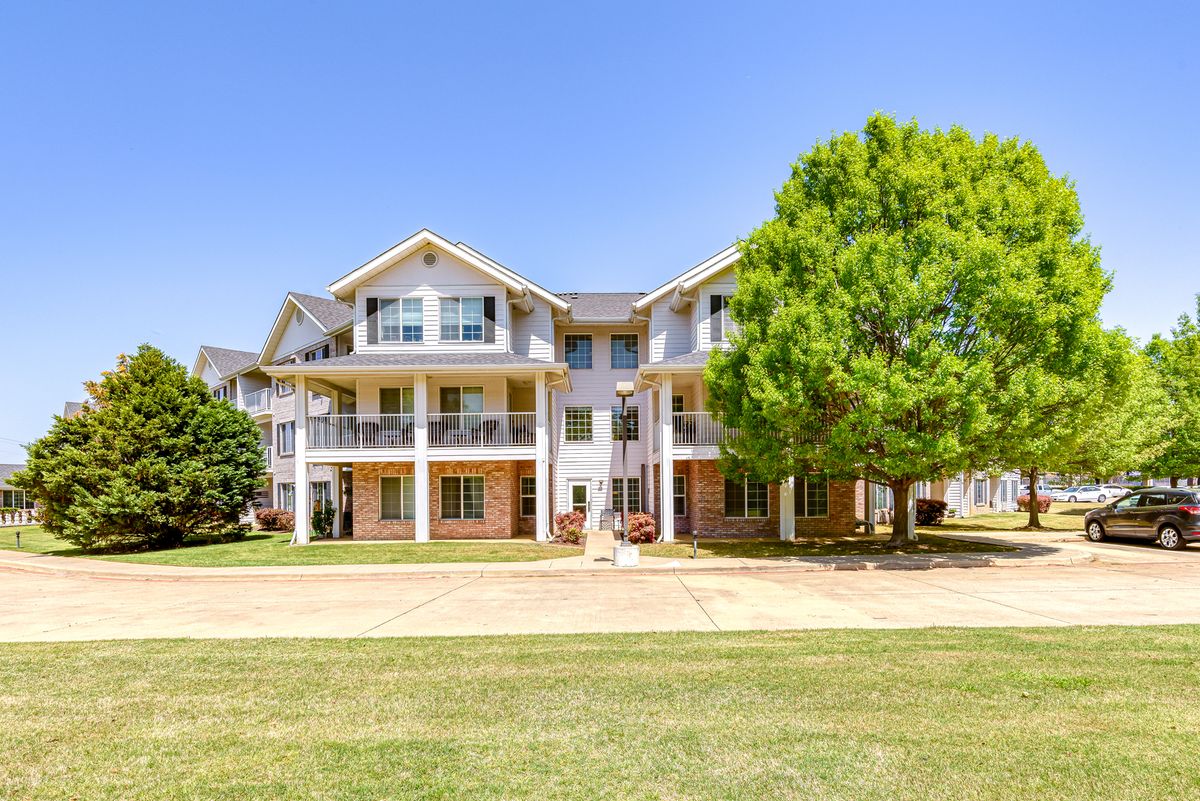 A large residential house with multiple stories and a spacious lawn under a clear blue sky.