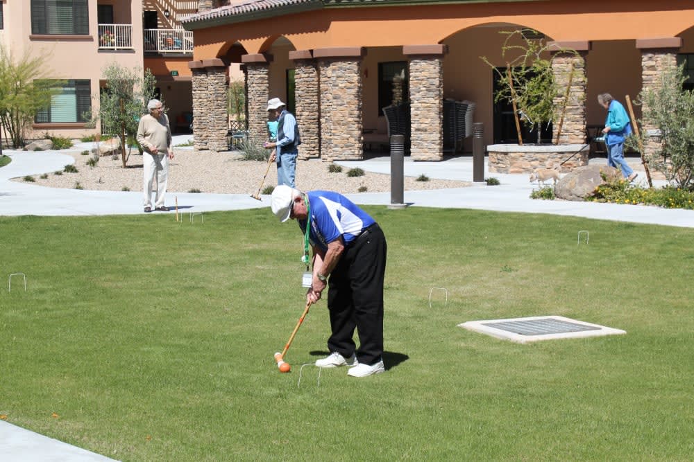A person preparing to putt on a golf course with buildings in the background.