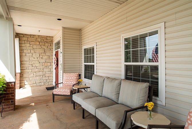 A cozy patio area with seating and a small side table adorned with flowers.