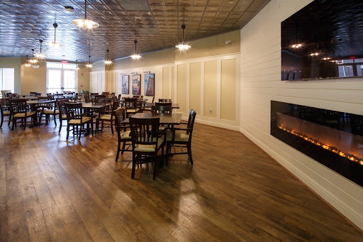 A cozy dining area featuring wooden floors, tables, and a fireplace, perfect for intimate gatherings.