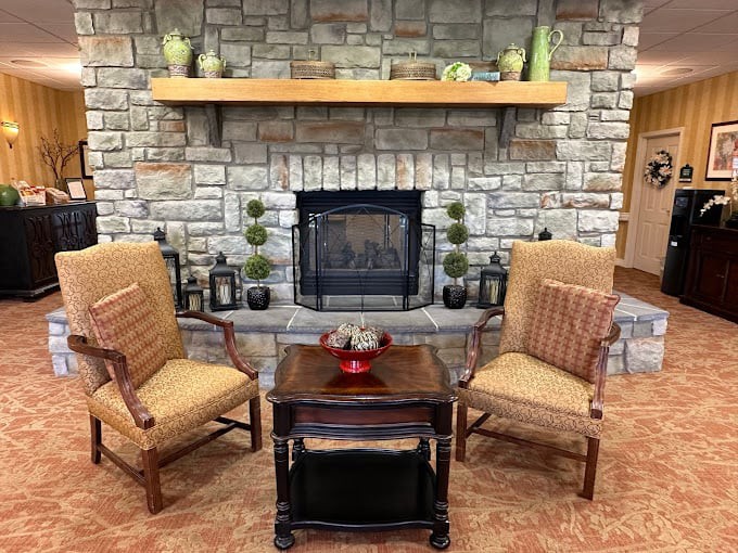 Cozy living room with two armchairs, a stone fireplace, and elegant decor.