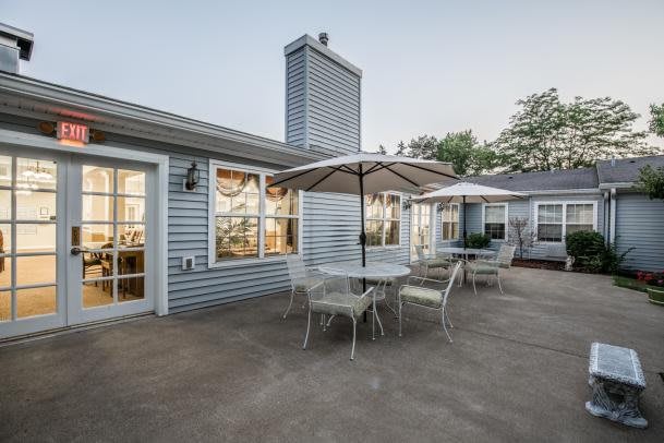 A spacious patio area with tables, chairs, and a large umbrella next to a house.