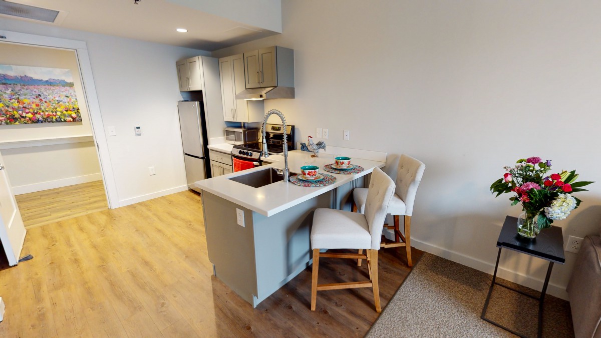 A modern apartment kitchen with a small island and barstools.