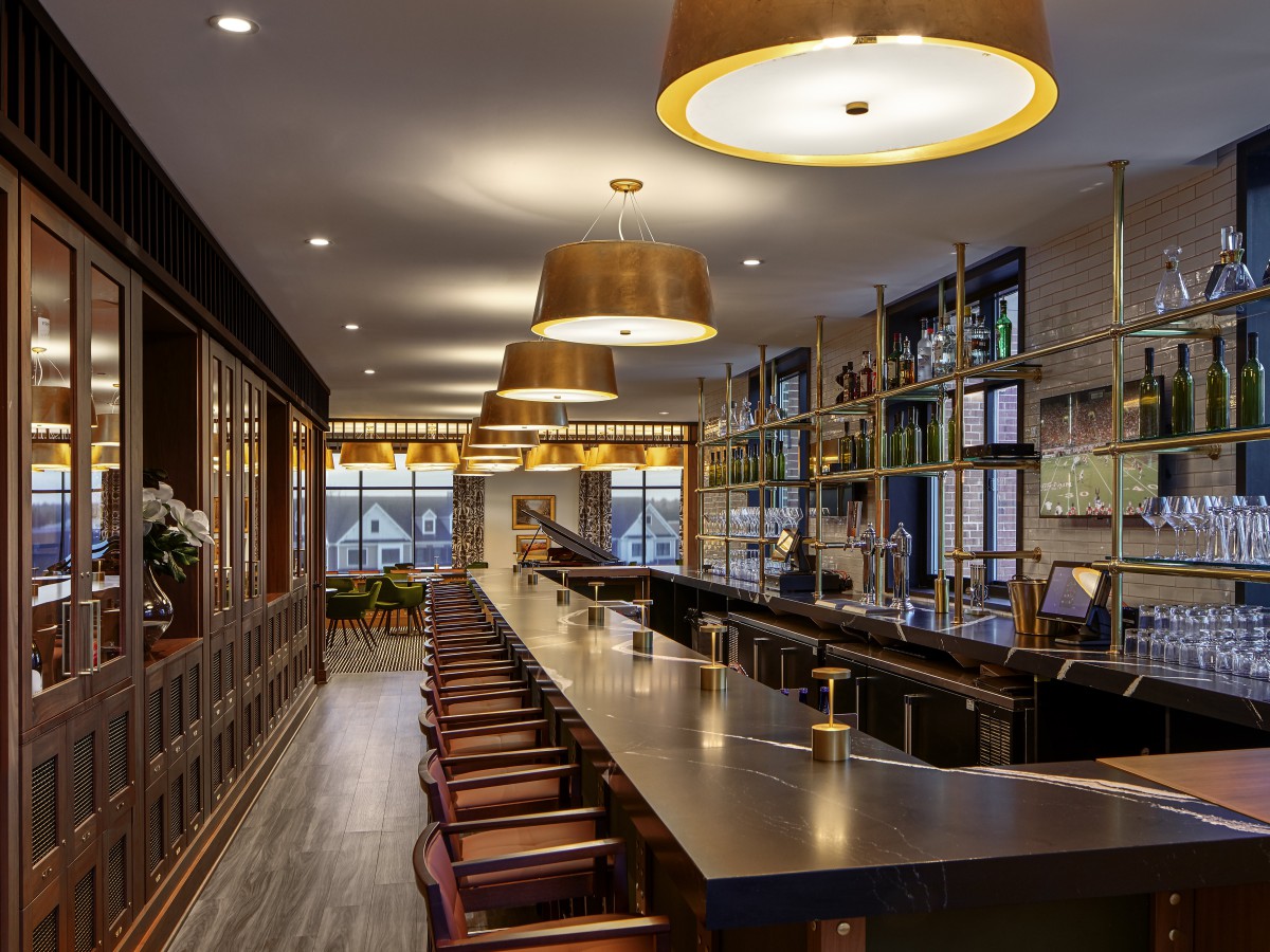 A modern bar interior with a long counter and elegant lighting.