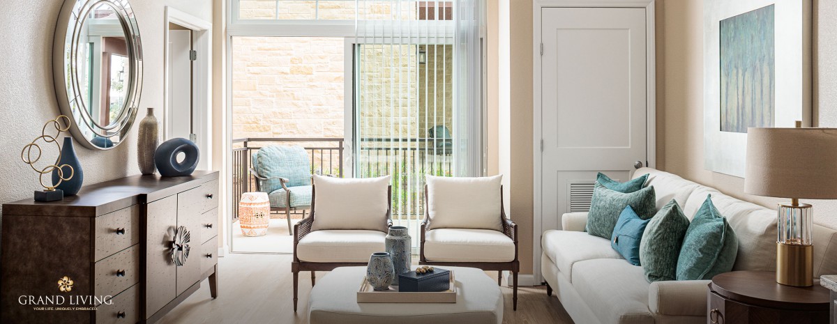 A modern living room featuring two armchairs and a coffee table near a large window with vertical blinds.
