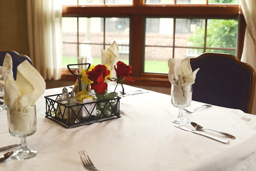 An elegantly set dining table featuring flowers and neatly arranged napkins, illuminated by natural light.