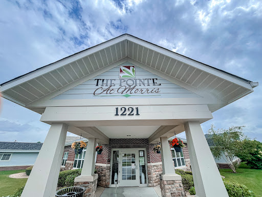The entrance of a business establishment showcasing modern architecture under a cloudy sky.