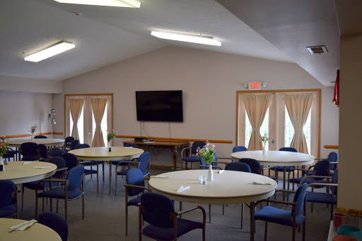 A spacious community meeting room with round tables and chairs arranged for gatherings.
