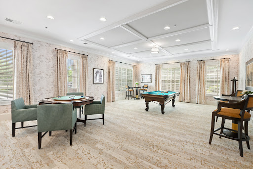 A spacious and elegantly designed game room featuring a pool table and a cozy dining area.