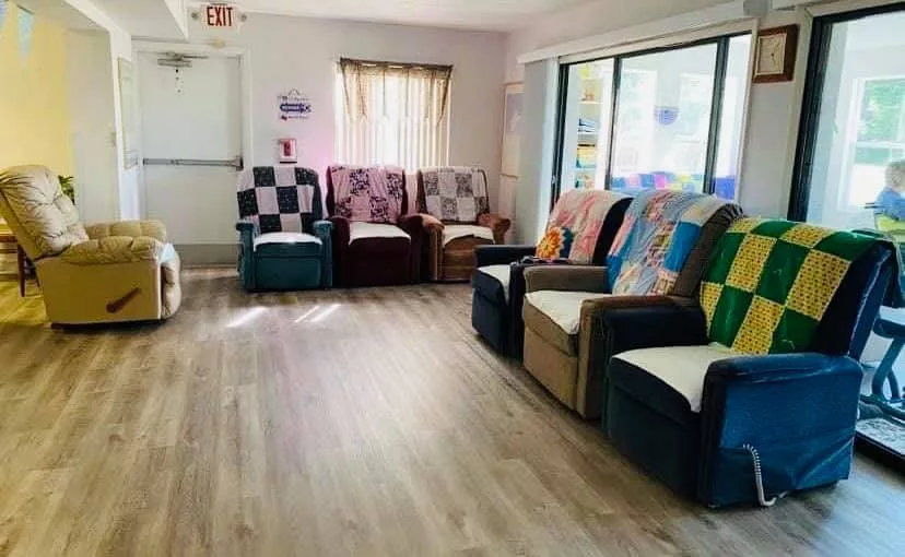 A cozy room with chairs adorned with colorful quilts by the windows.