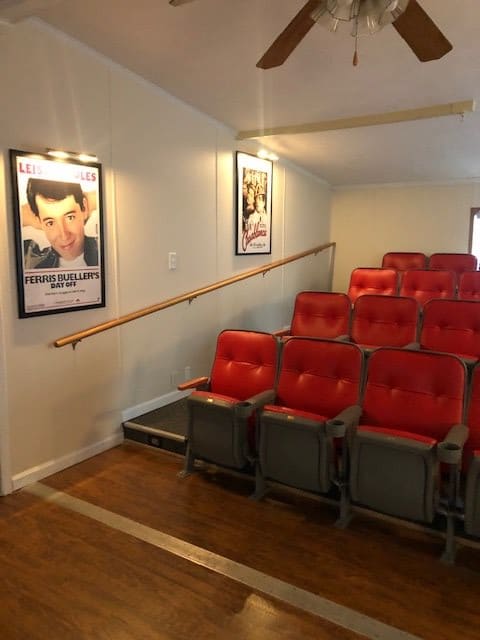 A small theater interior with red cushioned chairs and movie posters on the walls.