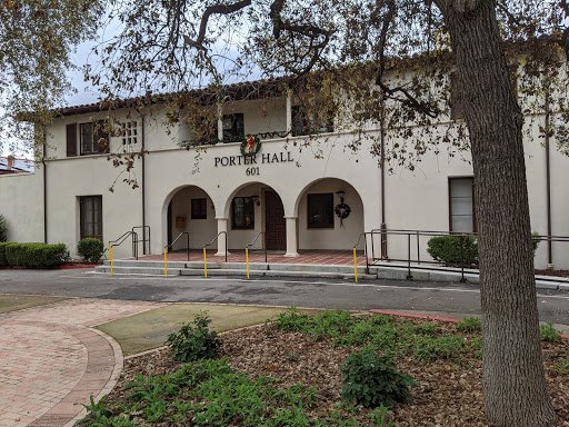 A view of the entrance to a building named 'Home Hall', featuring arched doorways and landscaped surroundings.