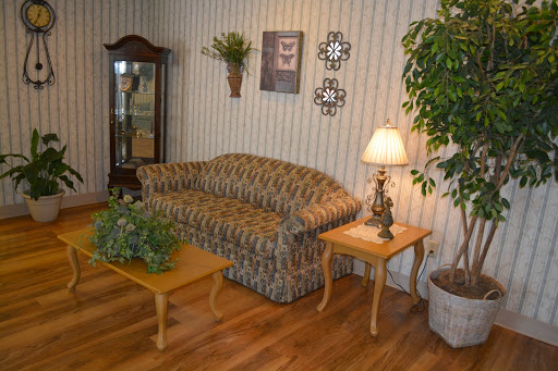 A cozy living room setup featuring a patterned sofa, wooden tables, and decorative plants.