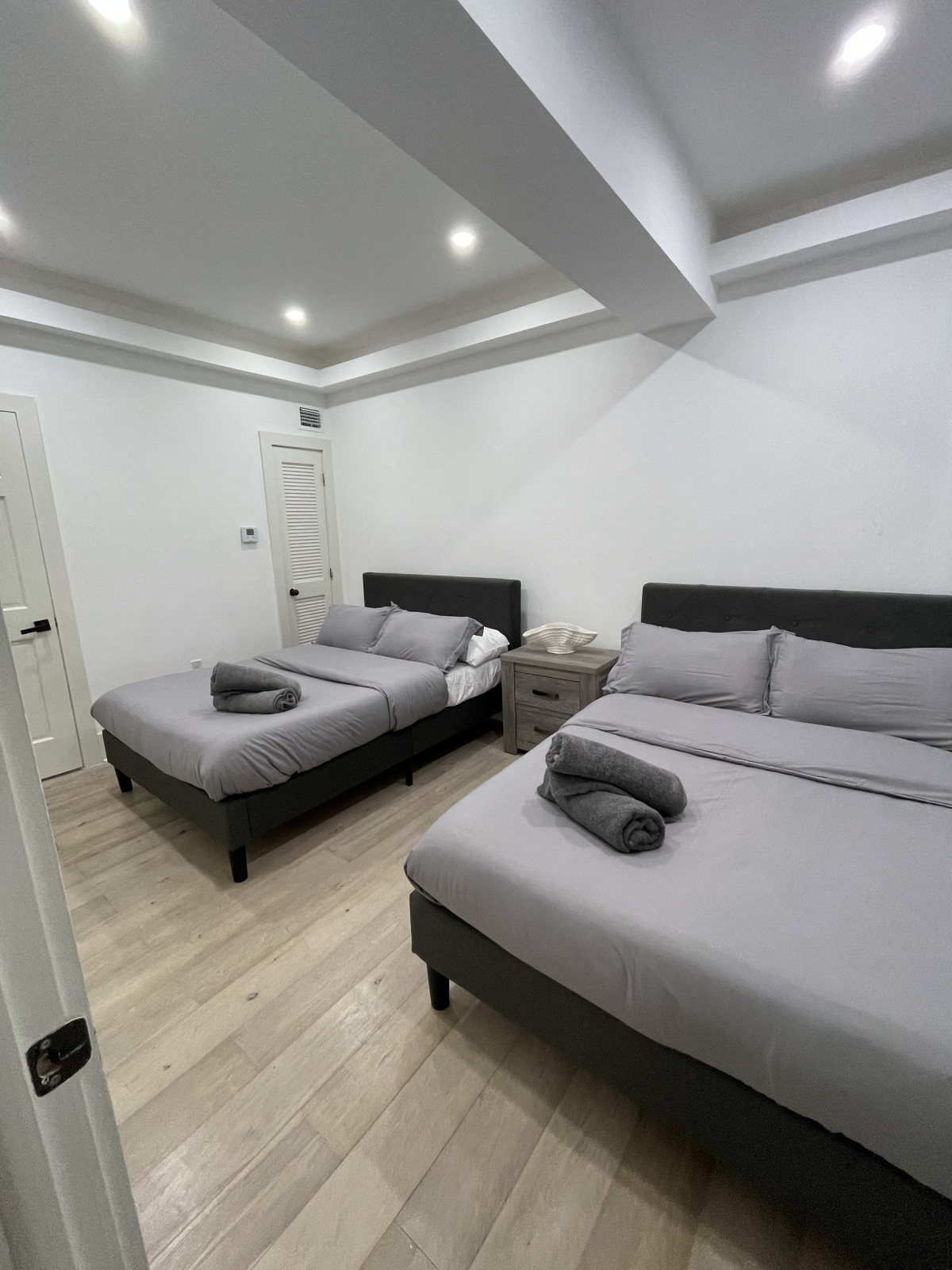 A modern and minimalist bedroom featuring two neatly made beds with gray bedding.