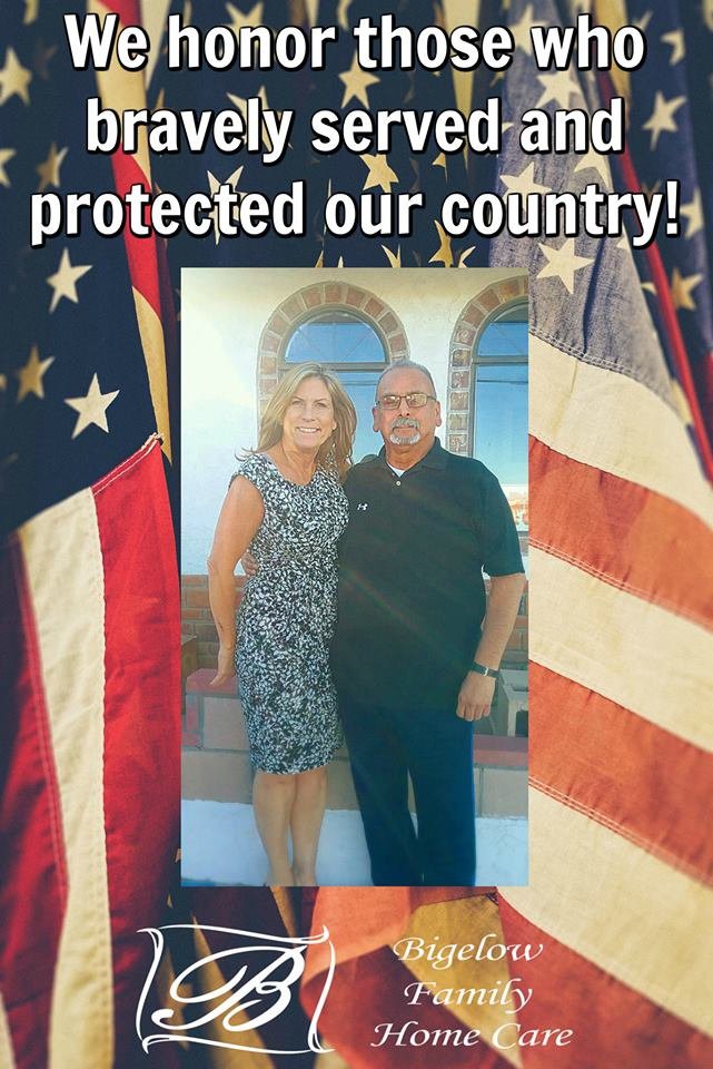 A couple stands proudly in front of American flags, symbolizing patriotism and gratitude for service.